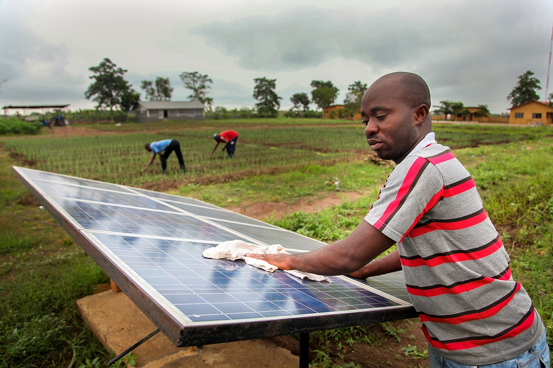 A man is cleaning a solar panel in Benin