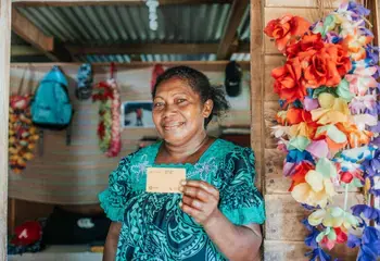 A woman shop keeper showing a credit card used for the Unblocked Cash programme in Vanuatu