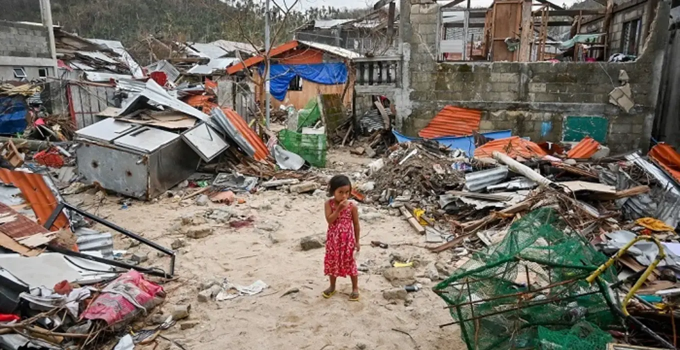 A child stands in the middle of her destroyed house in the Philippines 