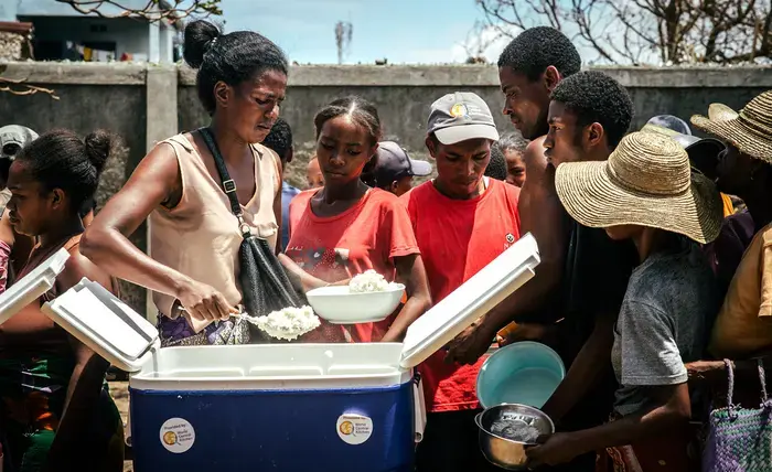 A malagasy woman distributes a hot meal to affected people after the cyclone in Mananjary