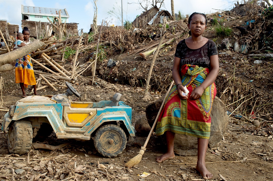 A lady sitting on the rubble of her damaged house