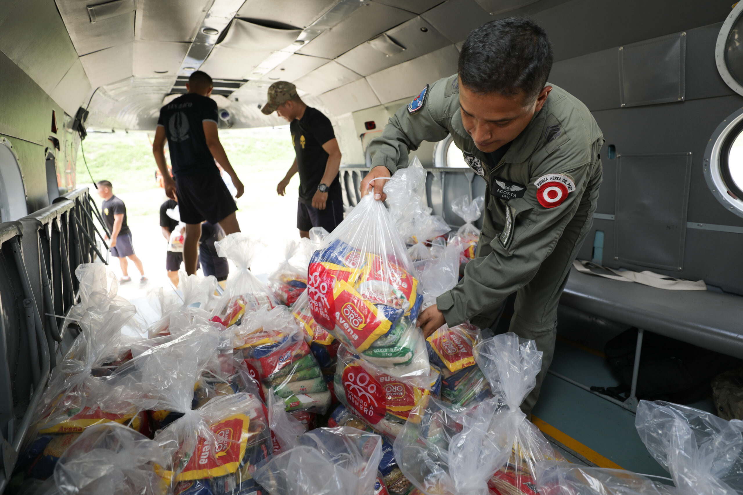 Men work together to move bags of aid from a helicopter out onto pickup trucks to get them to vulnerable and affected populations in hard-to-reach areas